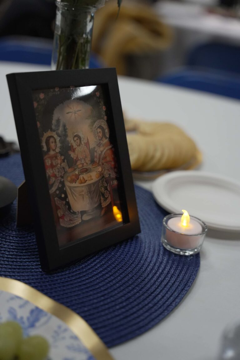 A set table with place mats and a framed photo of Jesus, Mary, and Joseph.