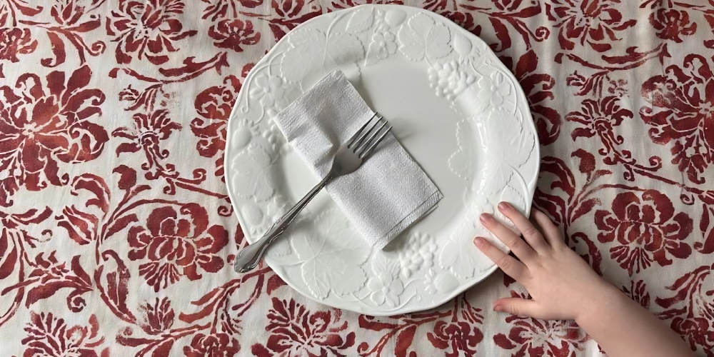 A child's hand reaches out towards a plate with a fork on it