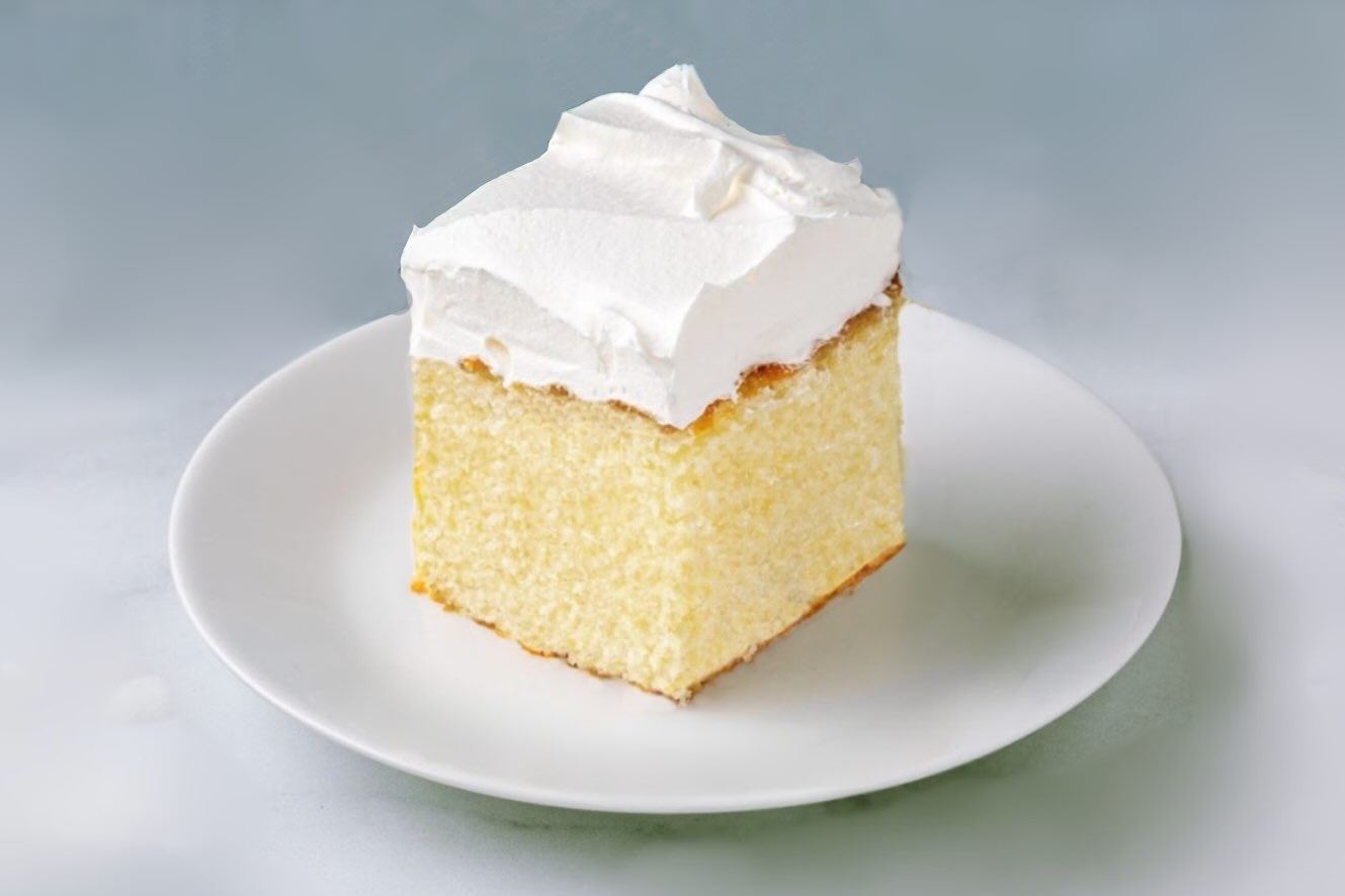 Square-shaped slice of cake with vanilla frosting on top