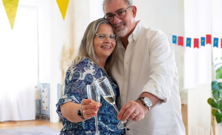 A man and a woman embracing side-by-side with champagne flutes.