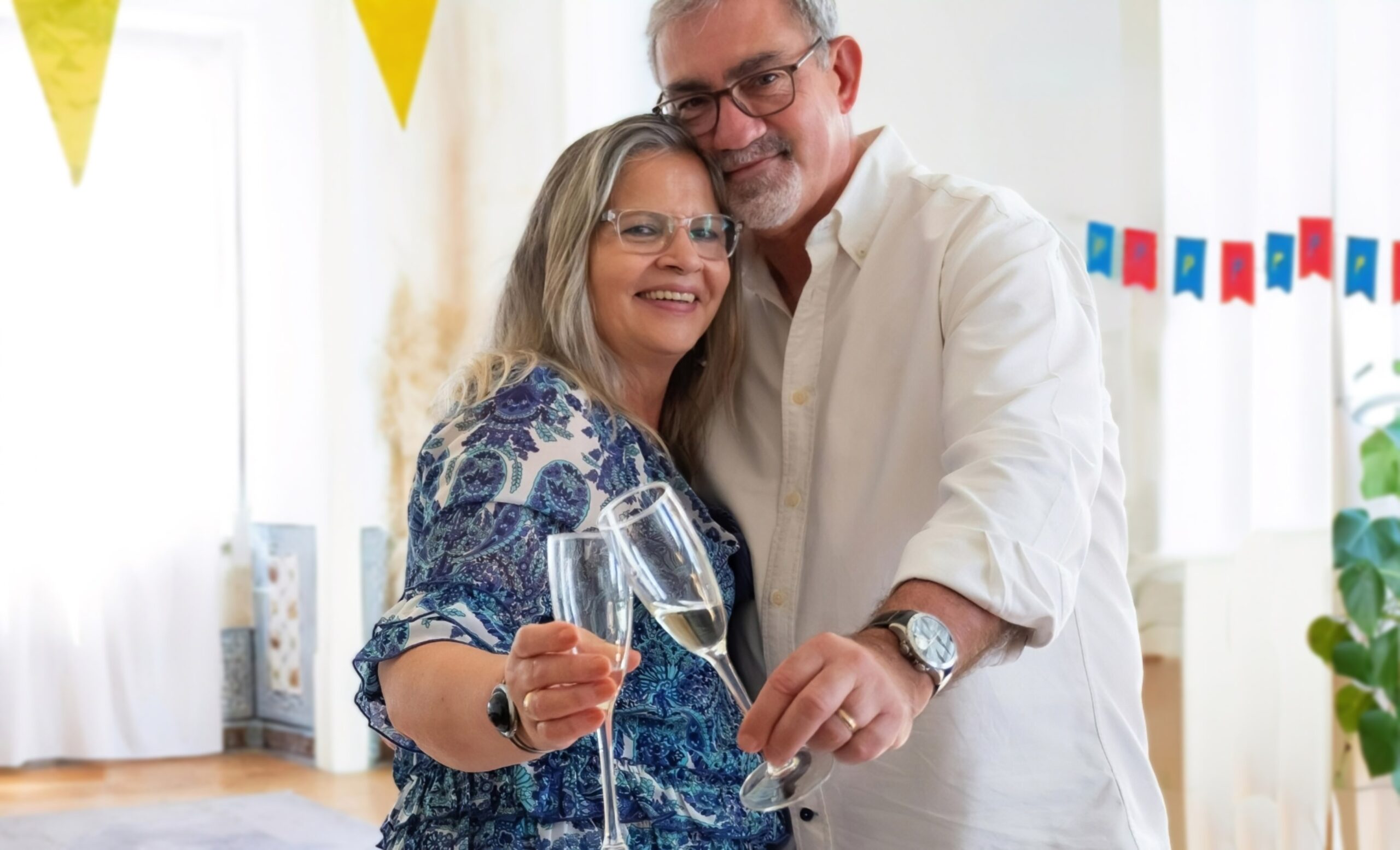 A man and a woman embracing side-by-side with champagne flutes.