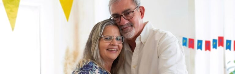 A man and a woman hugging with party decorations in the background.