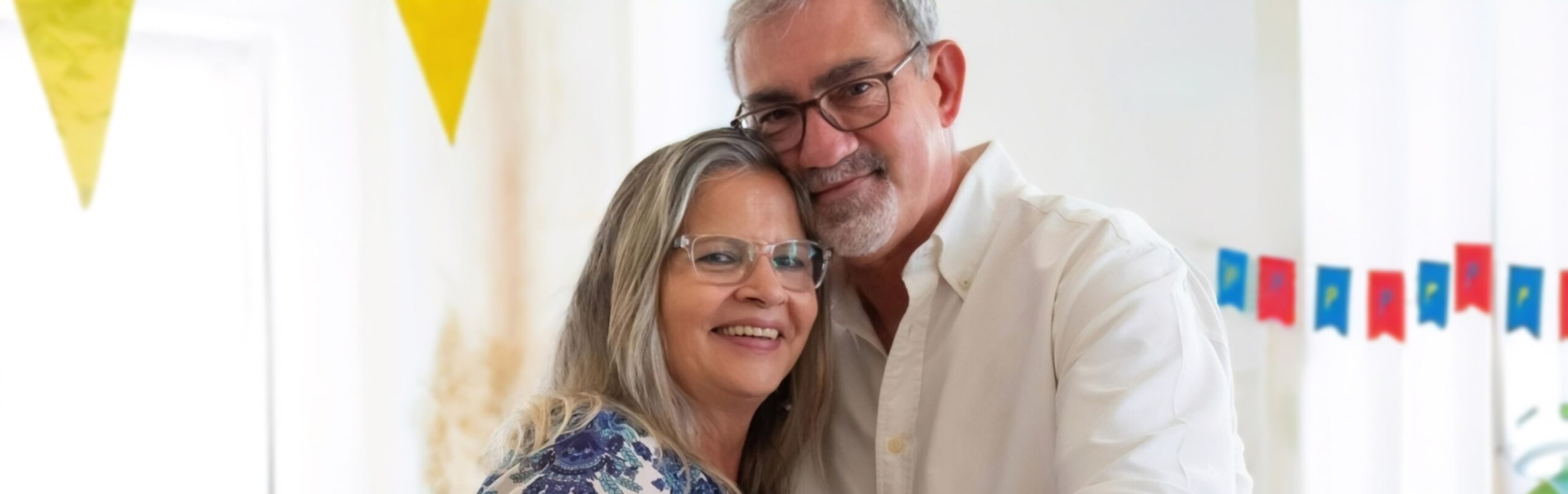 A man and a woman hugging with party decorations in the background.
