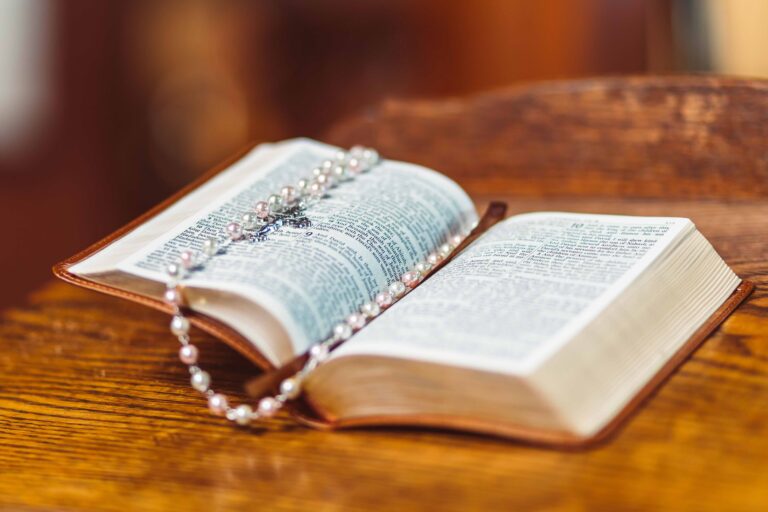 A bible opened to a page with a rosary laid across it.