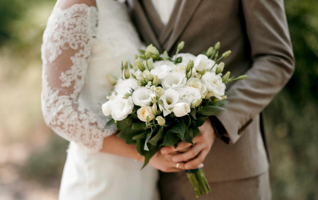 Two people in wedding attire hold a bouquet.