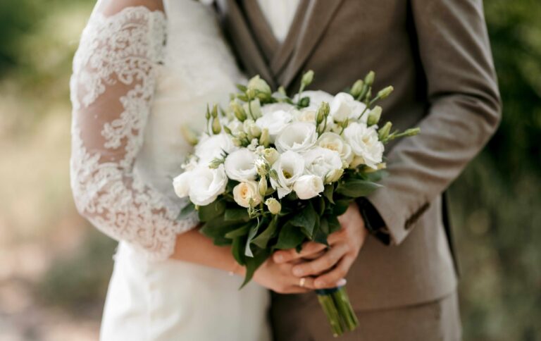 Two people in wedding attire hold a bouquet.